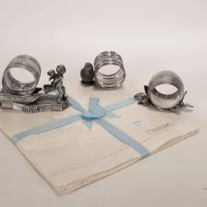Three antique Victorian silver plate napkin holders including cherub pulling a sledge, Easter chick 