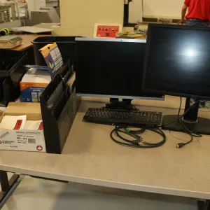 Selection of office supplies including two monitors, desk organization, GL570 printer, tape guns, et