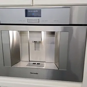 Thermador TCM24PS/09 built-in coffee maker. Features stainless steel finish, digital LCD display, and insulated milk container. 24"W. S/N: 71205020036