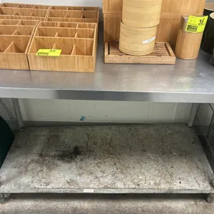 Stainless steel prep table. Features a flat top and solid undershelf. 60"L x 30"W. Mounted on tubular legs. Note: undershelf shows heavy staining. Con