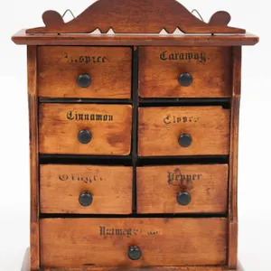 WOODEN SPICE CABINET WITH HAND-PAINTED LABELS.