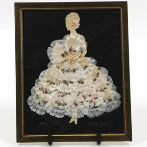 FRAMED RIBBON ARTWORK OF A WOMAN IN A DRESS.