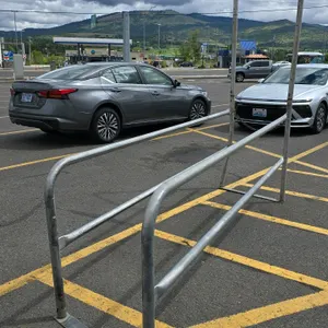 Galvanized steel cart corral. Features tubular frame construction and a "Please Return Shopping Carts Here" sign. 9'L x 2'W. Includes floor mount base
