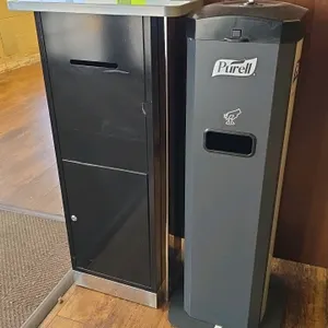 Package lot including (1) Purell freestanding wipe dispenser and (1) metal drop box kiosk. The dispenser features an integrated trash receptacle. The 