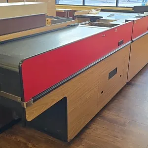 Reynolds Data 3000 Series dual belt checklane. Features red and woodgrain laminate finish, integrated rear storage shelving, and dual conveyor belts. 