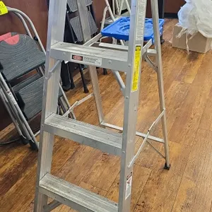Werner 4' aluminum folding step ladder. Features a blue plastic top, slip-resistant steps, and a fold-out tool tray.