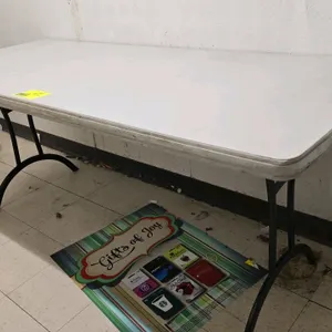 Poly folding table. Features a light gray top. 6'L. Mounted on a black metal folding base.