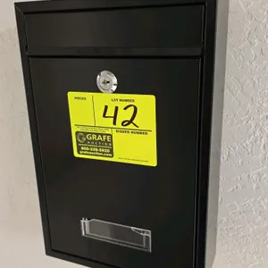 Metal wall-mounted dropbox. Features a black finish, top drop slot, locking door, and clear front window. 9" x 12".