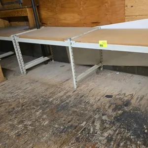 Warehouse racking. Features particle board decks and 2.5" crossbars. Measures 2.5'D x 2.5'H in 4'L sections. Background items not included.
