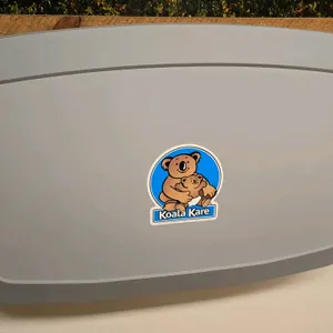 Koala Kare poly baby changing station. Features a wall-mounted fold-down design, safety strap, and built-in liner dispensers.