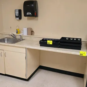 8'L laminate counter. Features a built-in stainless steel sink with faucet and a 2-door under-sink base cabinet. Includes wall-mounted manual paper to