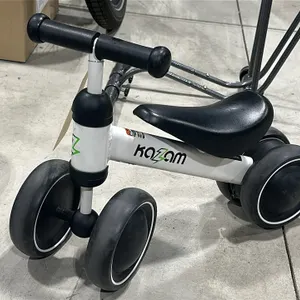 KaZam toddler ride-on bike. Features a white frame, black seat, and 4 wheels. Bike stand in background not included.