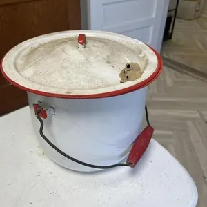 White enamel bucket with red trim and lid