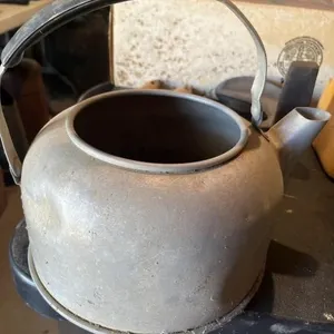Metal teapot missing lid has a dent