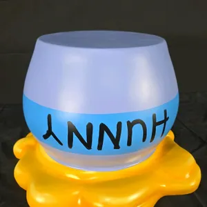 A Winnie the Pooh HUNNY Pot Sculpture. (Disney) A light blue pot mounted on a base resembling spilled yellow honey. Originally created for the Disney 