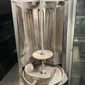 Autogyros 4LE stainless steel electric vertical gyro broiler. Features electric heating elements, a central spit assembly, drip pan, and a meat scoop.