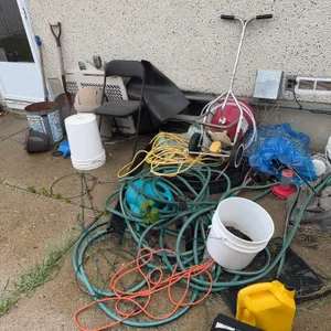 Various outdoor tools and garden equipment such as hoses, buckets, plastic containers, extension cor