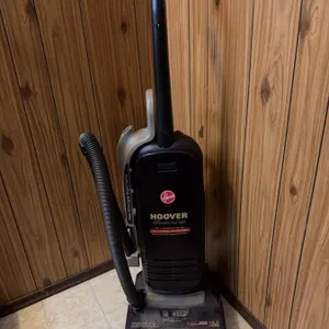 Hoover WindTunnel upright vacuum cleaner with attached hose. Features multi-stage filtration and Win