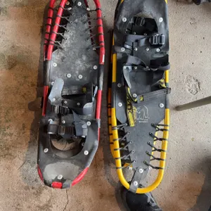 Adult snowshoes. One features a yellow frame with black deck, and the other a red frame with black d