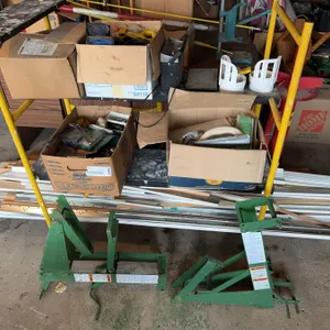 Two green metal drywall panel lifts, equipped with warning labels and hand cranks. Ideal for lifting