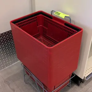 Red poly hand shopping basket. Features dual plastic handles and white store logo. 19"L x 13"W x 10"D. Includes a grey metal wire storage holder rack.