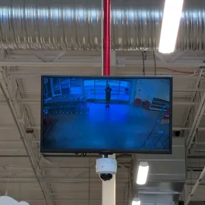 Insignia flat screen TV. Features an attached dome security camera. Approx. 28". Ceiling mounted.