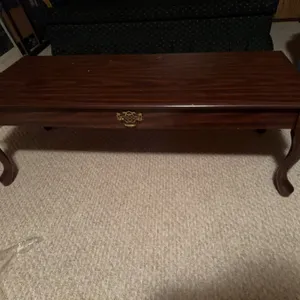 Rectangular wooden coffee table featuring a decorative brass-style drawer pull on the front and cabr