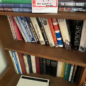 Books on shelf and below and battery charger