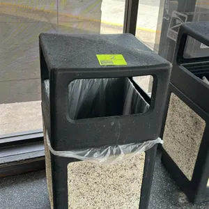Poly outdoor trash can. Features a black molded poly frame with decorative aggregate stone side panels. Designed with a dome-style top lid with side o
