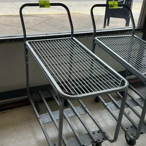 Metal 2-tier transport cart. Features a top wire-grid deck, a bottom slatted-metal deck, and an integrated push handle. Painted gray finish. 3'L. Mobi