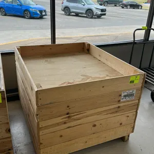Unbranded wood produce dump table. Features slatted wood construction with a recessed display deck and raised perimeter border. Mounted on a block-foo