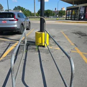 Metal single-row shopping cart corral. Features tubular steel construction designed for a single line of shopping carts. Open-ended entry with a raise