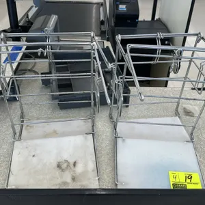 Metal wire bagger stand. Features chrome-plated steel wire construction with integrated hooks for plastic t-shirt grocery bags. Includes a plastic bas