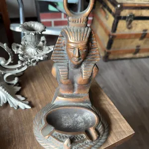 Two glass oil lamps, a metal two-arm candelabra, a ceramic or metal pharaoh-themed ashtray, a glass 