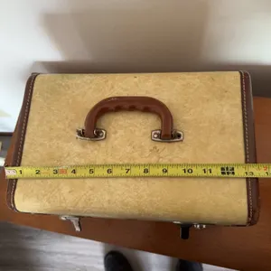 Calcraft Luggage Co. suitcase with a cream exterior, brown trim, metal hardware, and a brown handle.