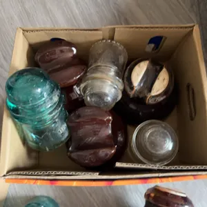 Lot containing several metal clamps and a variety of glass and ceramic electrical insulators in mixe