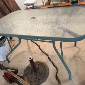 One rectangular glass-top patio table with a central umbrella hole and a metal frame, along with six