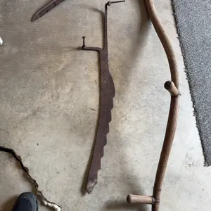 Traditional scythe with a wooden handle and metal blade, along with a metal adjustable hay rake atta