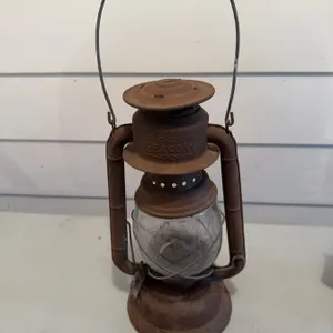 Beacon kerosene lantern made of metal with a clear glass globe and wire handle. Shows surface rust a