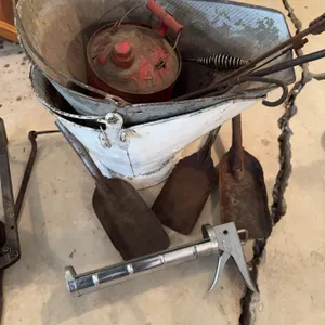 White metal bucket, red metal can with handle, three shovels, spring-handled tongs, and a metal grea