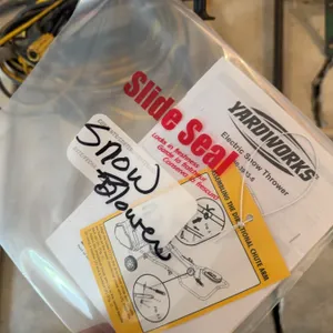 Yardworks electric snow thrower with attached yellow extension cord. Includes instruction manual and