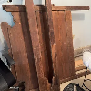 Disassembled wooden bed frame including headboard, footboard, and side rails. The frame shows wear a
