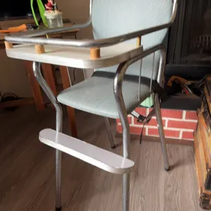 High chair with chrome metal frame, light blue upholstered vinyl seat and back, white footrest, and 