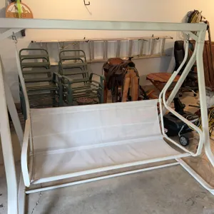 Outdoor swing featuring a cream-colored metal frame and mesh seat. Suitable for patio or garden use.