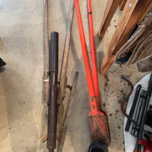 Multiple post hole diggers with wood and metal handles, a pair of long-handled red metal diggers, an