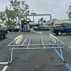 Metal shopping cart corral. Features a tubular metal frame with plastic side bumper panels and a dual-lane configuration. Includes an overhead arch fr
