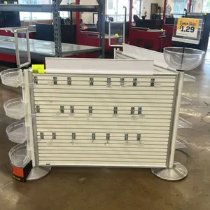 9'L slatwall merchandiser. Features a 3-section white slatwall configuration with metal frames. Includes clear plastic display bins, peg hooks, curved