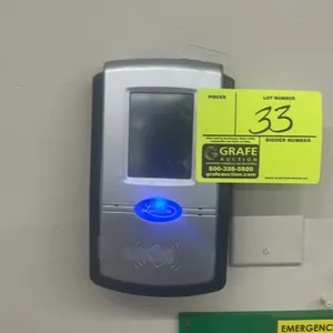 Lathem touchscreen time and attendance system. Features a digital display, integrated proximity badge reader, and illuminated logo. Wall-mounted desig