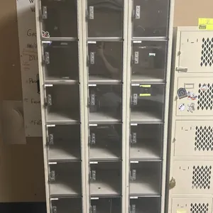 Metal 6-tier locker bank. Features 3 columns with 18 total compartments, clear doors, and metal latch handles. Dimensions per column: 12"W x 18"D x 78