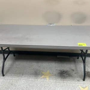 Polyethylene folding utility table. Features a gray plastic tabletop and black metal folding legs. 6'L.